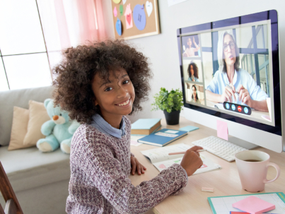 Cute small african kid girl looking at camera during social distance online class on video conference call with teacher, tutor and school children group learning at home. Elearning class on computer.