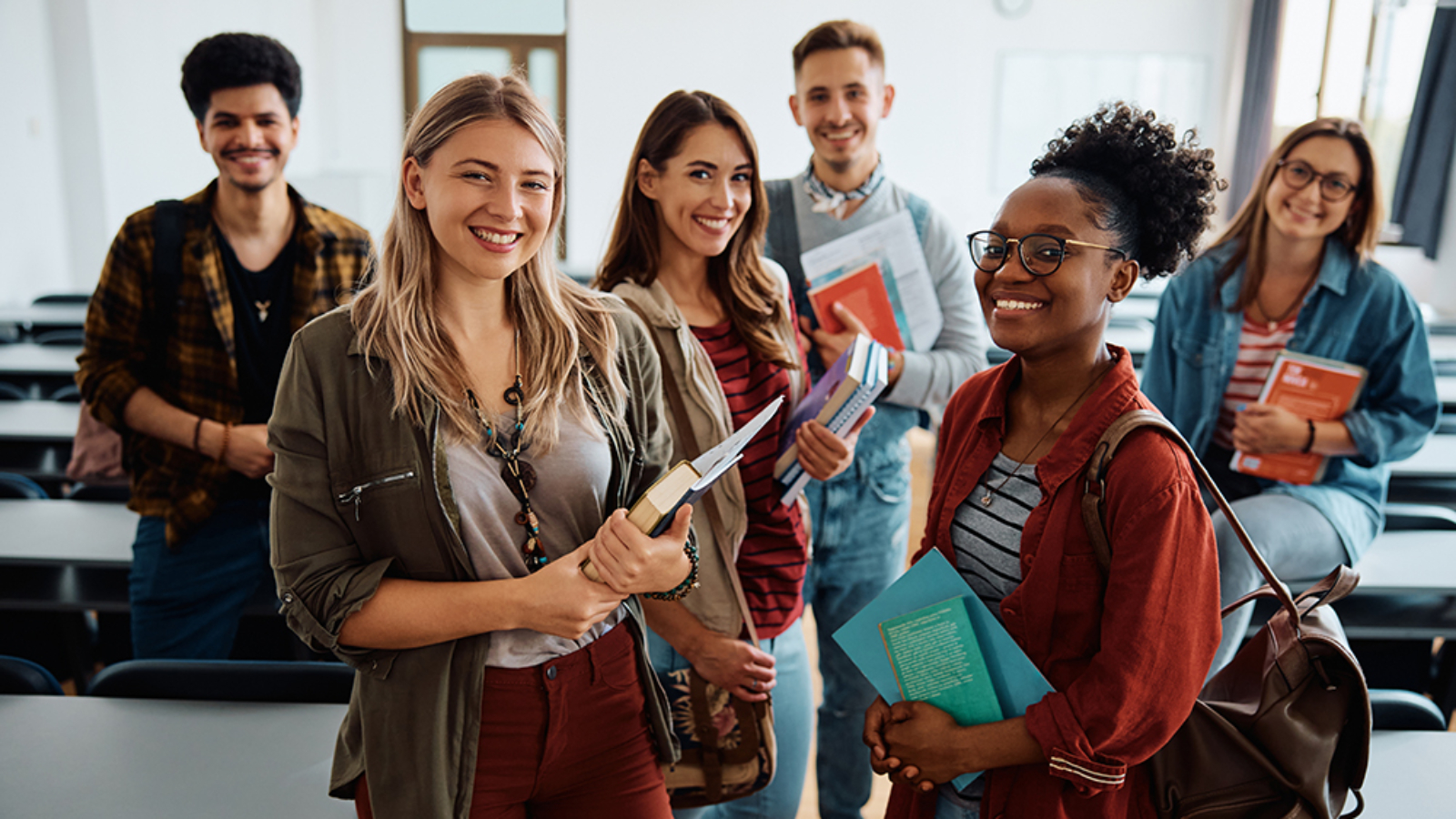 Multiracial group of happy college students int he classroom looking at camera.