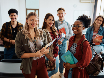 Multiracial group of happy college students int he classroom looking at camera.